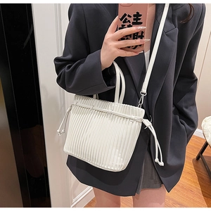 Detail of white pleated PU leather handbag featuring vertical folds and slim handle