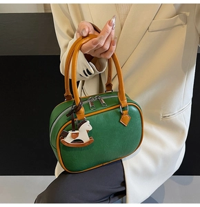 Detailed view of green PU crossbody bag with orange handles and cute horse pendant decor
