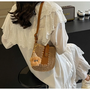 Straw crossbody bag with brown leather strap and cute dog pendant on white lace dress
