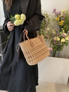 Close-up of natural straw handbag with brown leather handle and intricate woven patterns