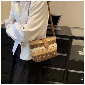 Detail der gewebten Stroh-Umhängetasche mit bunten Streifen und Leder-Schnallenverschluss