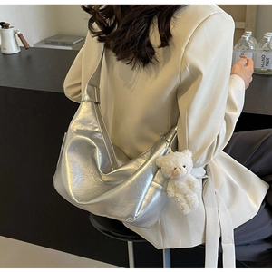 Dettaglio della borsa argento metallizzato con texture morbida e ciondolo orsetto bianco