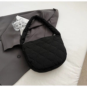 Minimalist black quilted nylon shoulder bag with wavy stitch design on a blazer background