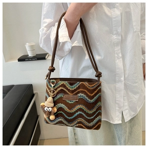 Detail of colorful woven shoulder bag with a plush monster charm and knotted strap