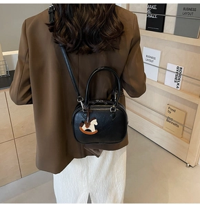 Close-up of stylish black PU crossbody bag with double zippers and cute rocking horse charm