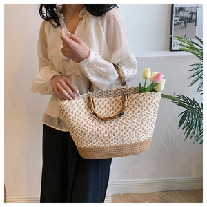 Detail of woven straw tote bag with bamboo handles and fresh tulips inside for a resort look