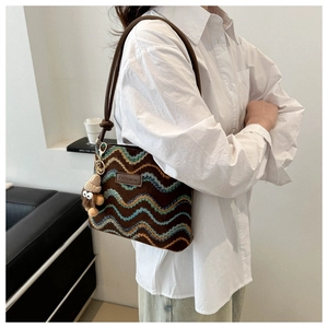 Detail of cross-body bag with wavy embroidery, leather fashion patch, and plush charm