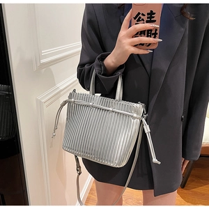 Close-up of metallic silver pleated bag with drawstring detail and slim shoulder strap
