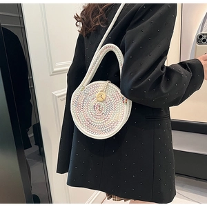 Detail of white woven crossbody bag with colorful wavy stitching and gold circular buckle