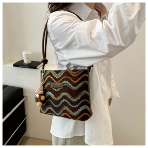 Detail of retro wave embroidered crossbody bag in brown fabric with a cute plush charm