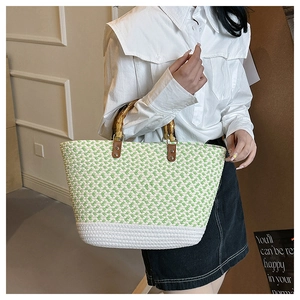 Detail of the woven tote bag featuring a green and white pattern with natural bamboo handles