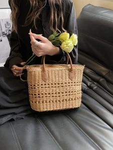 Detail of hand-woven straw bag with leather handle and decorative yellow flowers