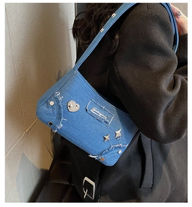 Détail du sac à bandoulière en denim bleu avec patchs cœur et étoile sur manteau noir