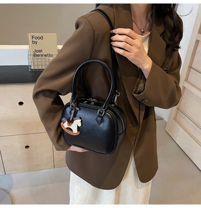 Close-up of black PU leather crossbody bag with dual zippers and wooden horse charm