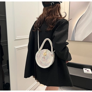 Colorful hand-woven round crossbody bag with golden buckle on model in black suit
