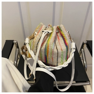 Colorful striped canvas drawstring bucket bag with a plush bear charm on a black chair