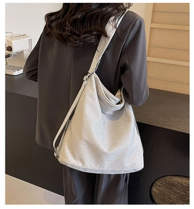 Close-up of silver glitter hobo bag with wide shoulder strap on a model at a cafe