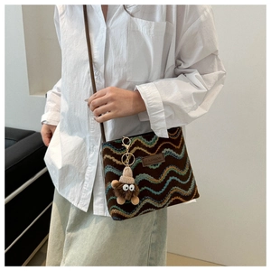 Detailed view of wave-pattern knit crossbody bag featuring a cute plush bear charm