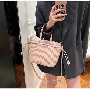 Detail of dust pink pleated PU leather handbag featuring side drawstring closures
