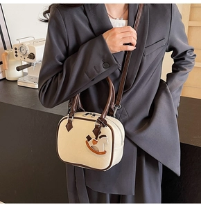 Detail of cream white PU leather crossbody bag with wooden horse charm and brown handles