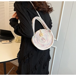 Detail of round woven shoulder bag with rainbow stitching and a wooden button closure