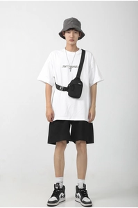 Detail of a black oxford fabric crossbody bag styled with a casual streetwear outfit
