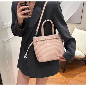 Detail of pink pleated PU leather crossbody bag featuring elegant vertical accordion texture