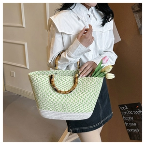 Detail of hand-woven green and white checkered tote bag with natural bamboo handles