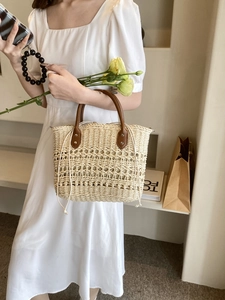 Detail of woven straw handbag featuring premium leather handles and a secure drawstring liner