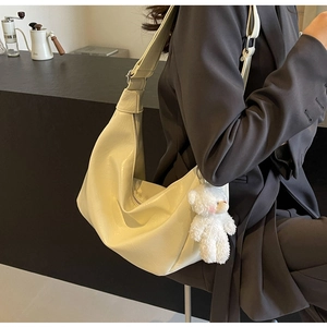 Dettaglio borsa hobo beige in pelle sintetica con ciondolo a forma di orsetto e tracolla