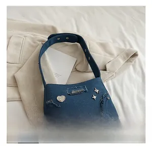 Gros plan du sac à bandoulière en jean avec bords effilochés vintage et breloques en cœur