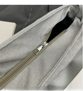 Detail shot of smooth silver glitter fabric and durable metal zipper on a fashion handbag