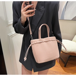 Detail of pink pleated mini tote bag with adjustable shoulder strap and drawstring knot