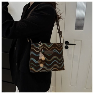 Close-up of brown woven crossbody bag with colorful wavy patterns and fashion label