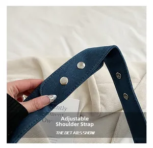Détail d'une bandoulière en denim réglable avec boutons-pression argentés sur un sac bleu