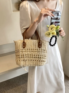 Close-up of woven straw handbag with brown leather handles and interior drawstring pouch