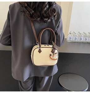 Chic cream PU leather crossbody bag with brown trim and wooden horse charm on a grey blazer