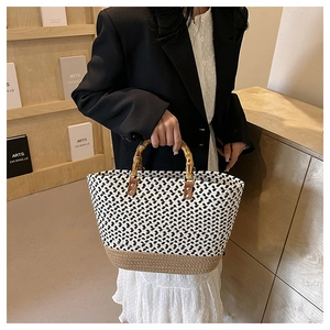 Detail of woven tote bag featuring a bamboo handle and contrast stitch texture