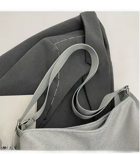 Detail shot of shimmering silver PU shoulder bag with durable woven strap and metal hardware