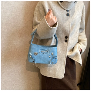 Détail d'un mini sac en denim bleu clair orné de rivets métalliques en forme de cœur et d'étoile