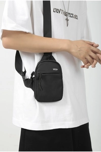 Detailed view of black Oxford fabric crossbody bag with adjustable wide strap and zip pocket