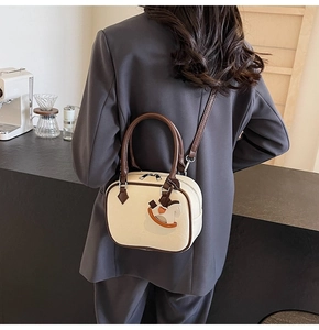 Detail of a creamy white PU leather mini bag with dark brown trim and cute rocking horse charm