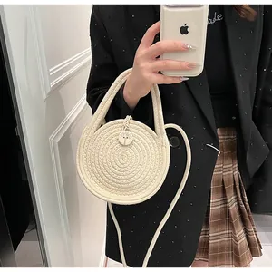 Detail of round woven straw handbag with a decorative tree-patterned wooden button