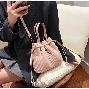 Detail of light pink pleated bucket bag in soft PU leather with drawstring closure