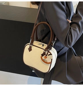 Detail view of cream PU leather mini bag with dark brown trim and wooden horse charm
