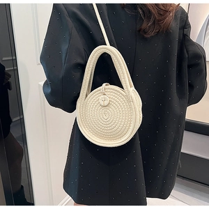 Detailed view of woven linen crossbody bag with round button and spiral braided texture