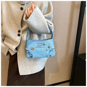 Gros plan détaillé du sac en denim bleu avec logo coeur en métal et rivets en étoile