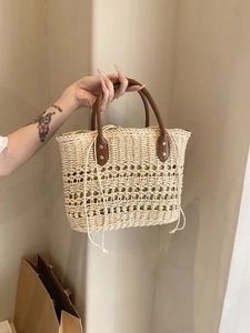 Detailed straw handbag weave with brown leather handle and drawstring inner lining