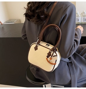 Detail of cream PU leather Boston bag with contrast brown handles and horse charm