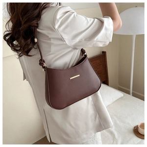 Detail view of dark brown PU leather shoulder bag with gold metal bar and knotted strap